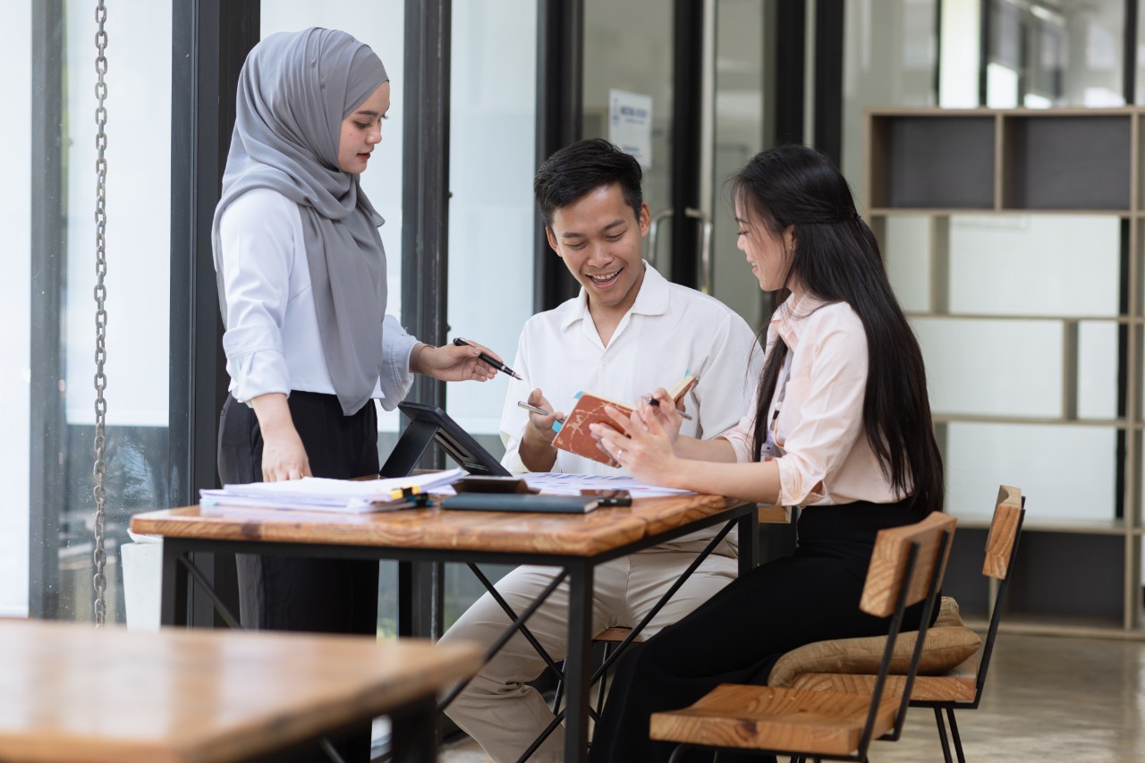 Group of Asian students talking in meeting about projects.