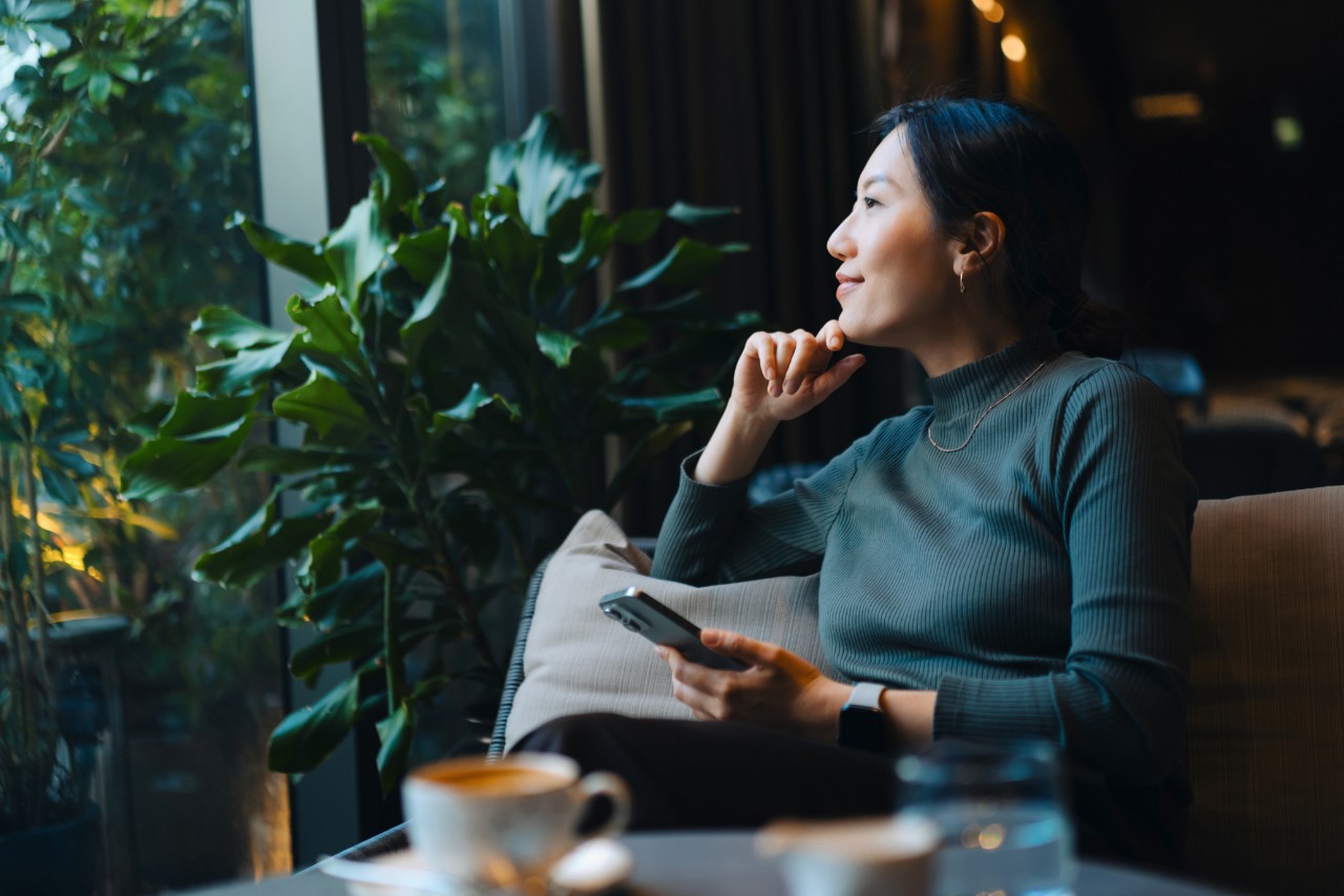 Confident young A out through window while sitting in a cafe having coffee. Making a personal financial plans and investment decisions. Wealth management. Business, banking, finance and investment concept
